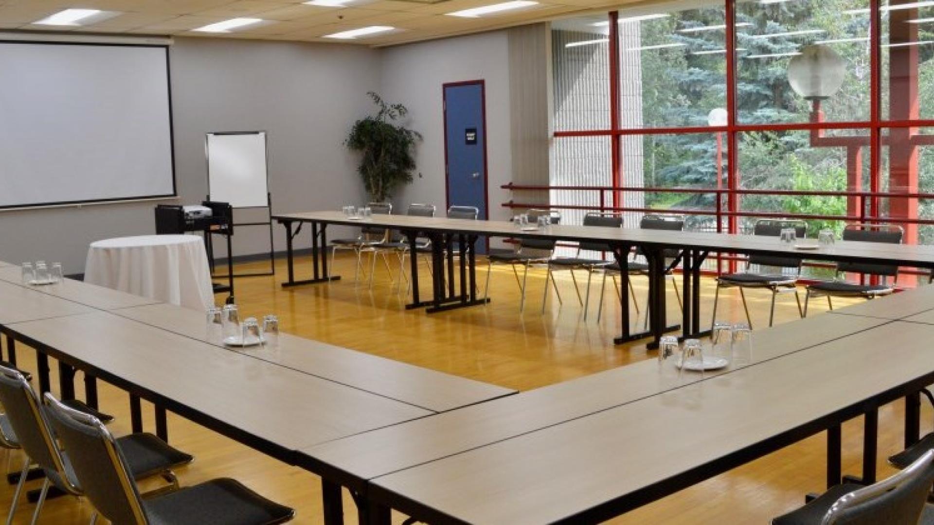 Meeting room with desks and chairs in a circle around a projector screen