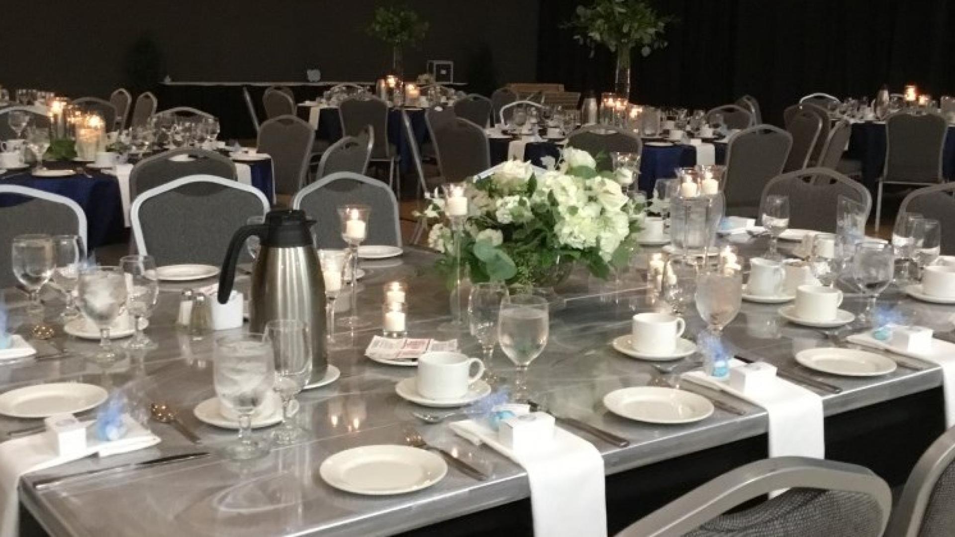 Tables and chairs set for a formal dinner, with flowers, candles, and cloth napkins