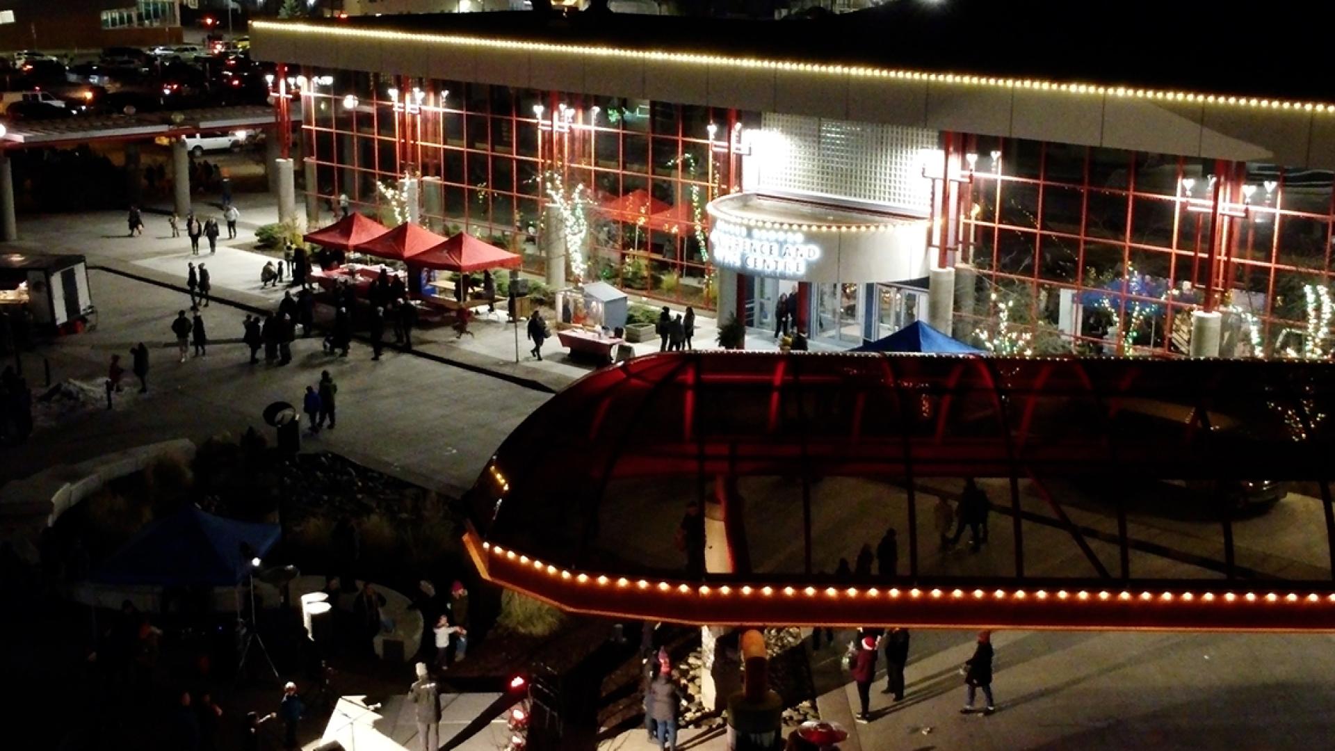 Aerial view of Canada Games Plaza in at night, with crowd and holiday lights.