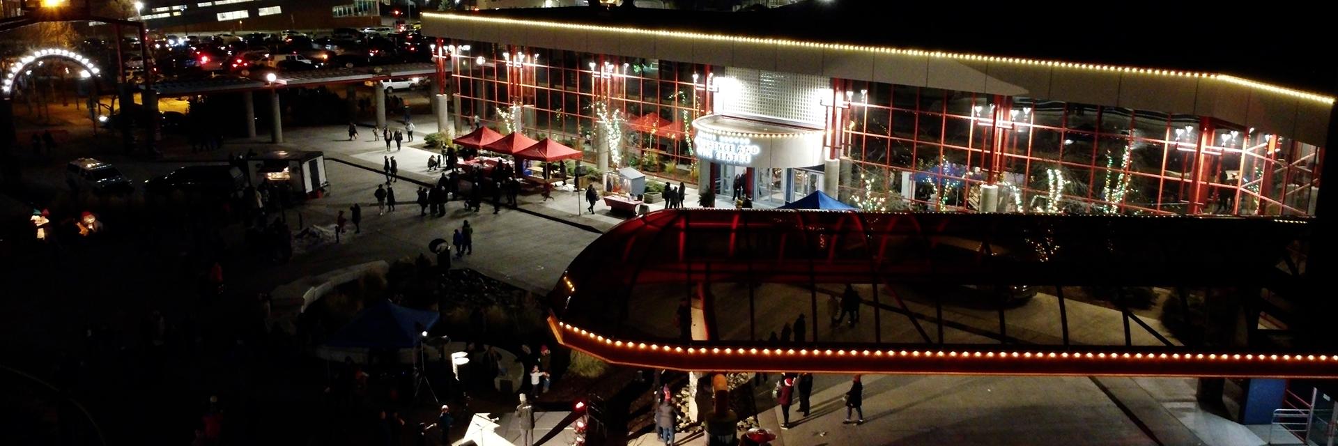 Aerial view of Canada Games Plaza in at night, with crowd and holiday lights.