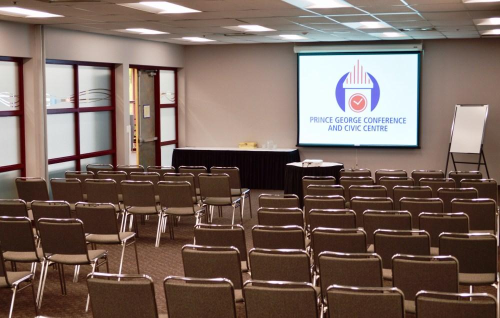 Upper floor meeting room, with rows of chairs facing a projection screen at the front of the room
